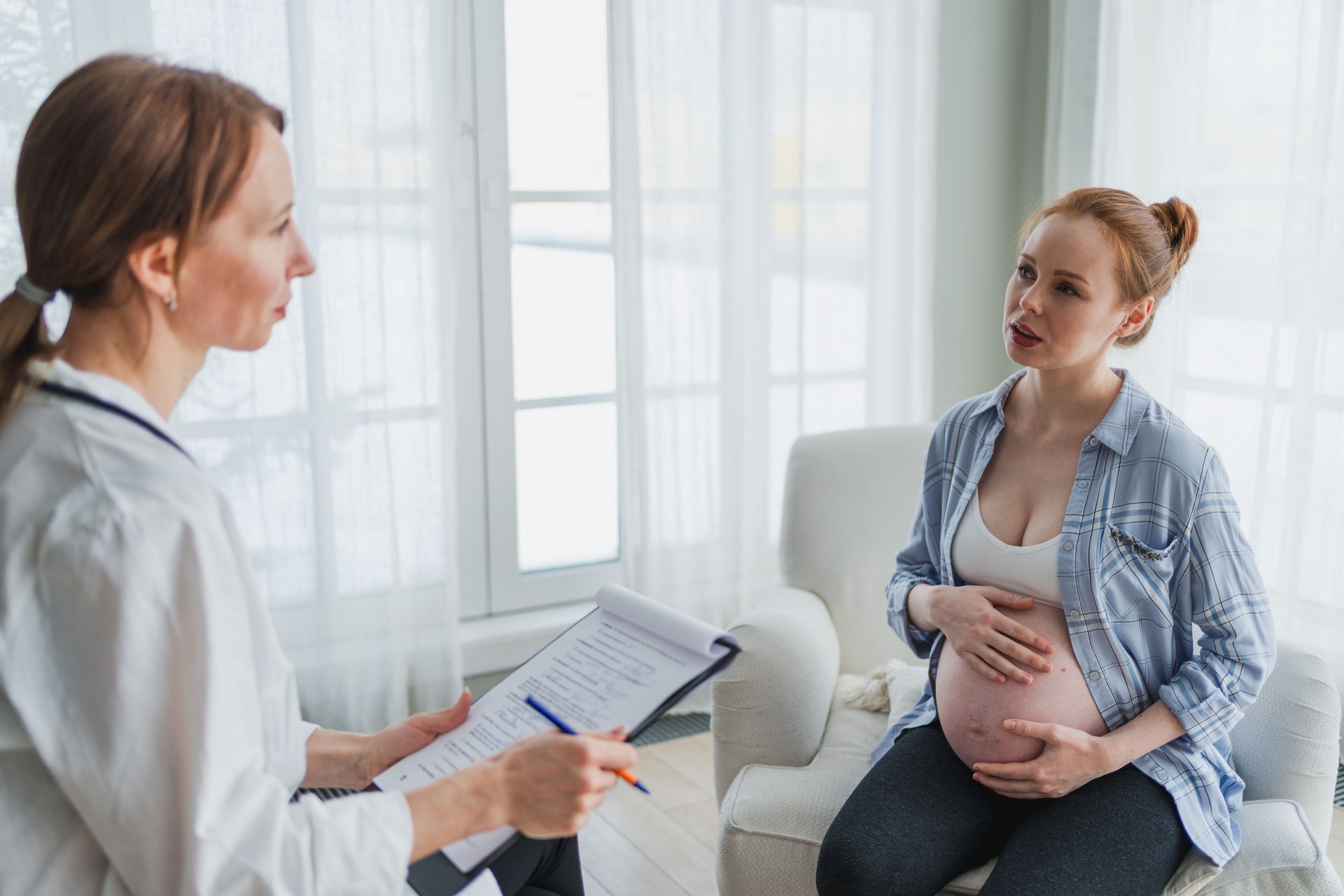 Female doctor examining pregnant woman in doctor office. Pregnant girl patient have consultation in hospital. Gynecologist doctor consulting patient about pregnancy. Visit to doctor medical checkup.
