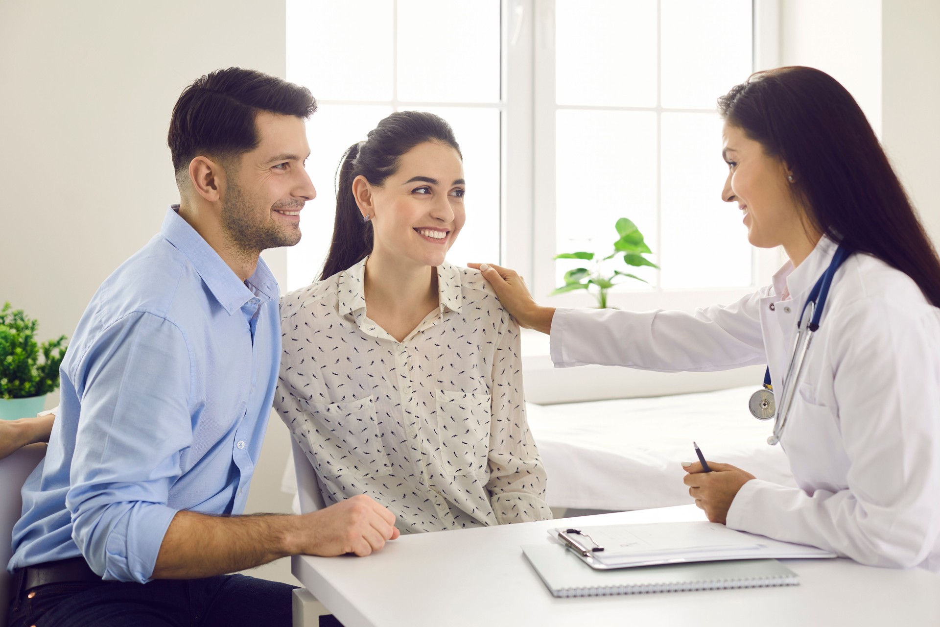 Female doctor consulting young couple patients in fertility clinic about IVF or IUI.